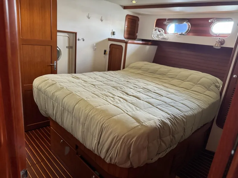 Slide: The Image of Cozy bedroom in 2003 Nordhavn N46 yacht with wooden accents and porthole windows. - 24