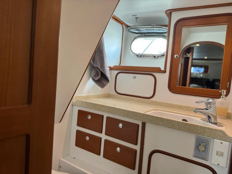 Slide: The Image of Bathroom interior of a 2003 Nordhavn N46 yacht, featuring wooden cabinetry and a porthole window. - 25