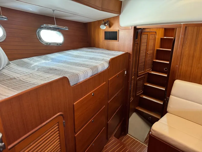 Slide: The Image of 2003 Nordhavn N46 cabin interior with wooden finish, bed, and seating area. - 26