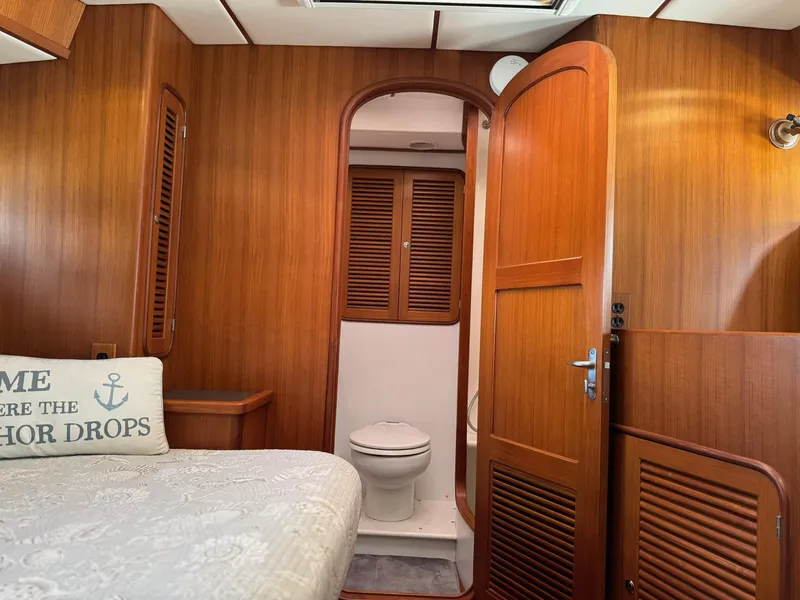 Slide: The Image of 2003 Nordhavn N46 yacht interior with wooden paneling, bed, and bathroom. - 29
