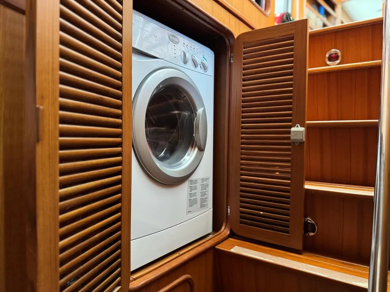 Slide: The Image of Washing machine in 2003 Nordhavn N46 yacht's wooden cabinet with open louvered door. - 31
