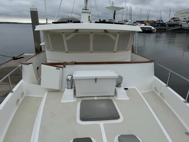 Slide: The Image of 2003 Nordhavn N46 yacht docked, showcasing spacious deck and pilothouse under cloudy skies. - 6