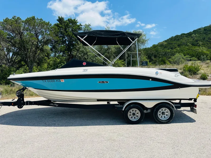 Slide: The Image of 2022 Sea Ray SPX 210 boat on trailer, blue and white, parked outdoors. - 16