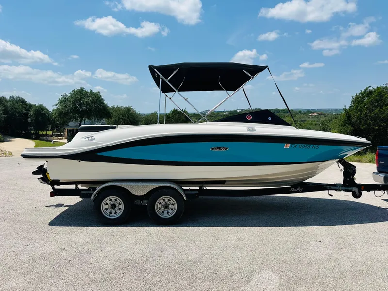 Slide: The Image of 2022 Sea Ray SPX 210 boat on trailer, blue and white, parked outdoors under clear sky. - 18