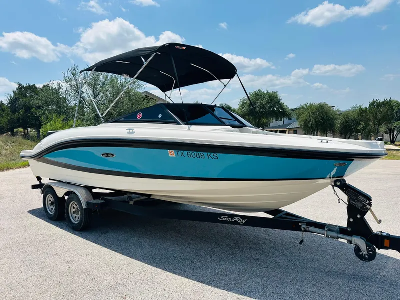 Slide: The Image of 2022 Sea Ray SPX 210 boat on trailer, blue and white, parked outdoors. - 19