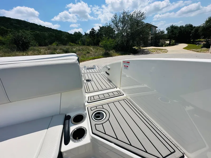 Slide: The Image of 2022 Sea Ray SPX 210 boat interior with cup holders and sleek seating under a sunny sky. - 23