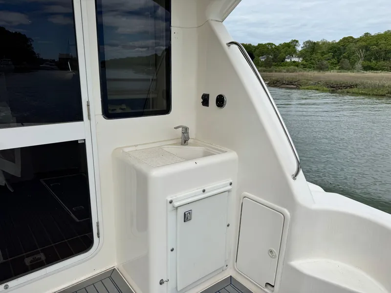Slide: The Image of 2005 Riviera 33 Flybridge yacht with outdoor sink and storage, docked by serene waters. - 12