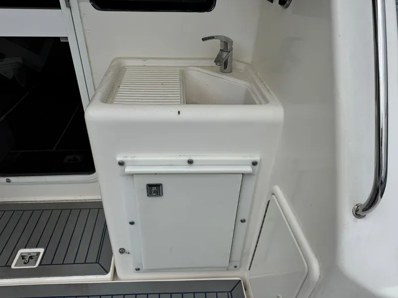 Slide: The Image of Compact sink area on 2005 Riviera 33 Flybridge yacht, featuring faucet and storage cabinet. - 13