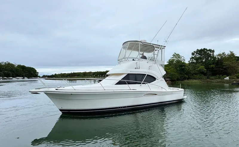 Slide: The Image of 2005 Riviera 33 Flybridge yacht on calm water, overcast sky. - 2