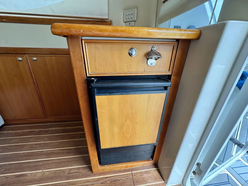 Slide: The Image of 2005 Riviera 33 Flybridge interior with wooden cabinetry and compact fridge. - 21