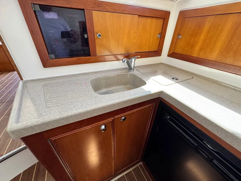 Slide: The Image of 2005 Riviera 33 Flybridge yacht kitchen with sink, wooden cabinets, and countertop. - 27