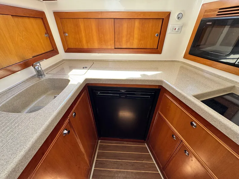 Slide: The Image of 2005 Riviera 33 Flybridge kitchen with wooden cabinets, modern appliances, and sleek countertops. - 29