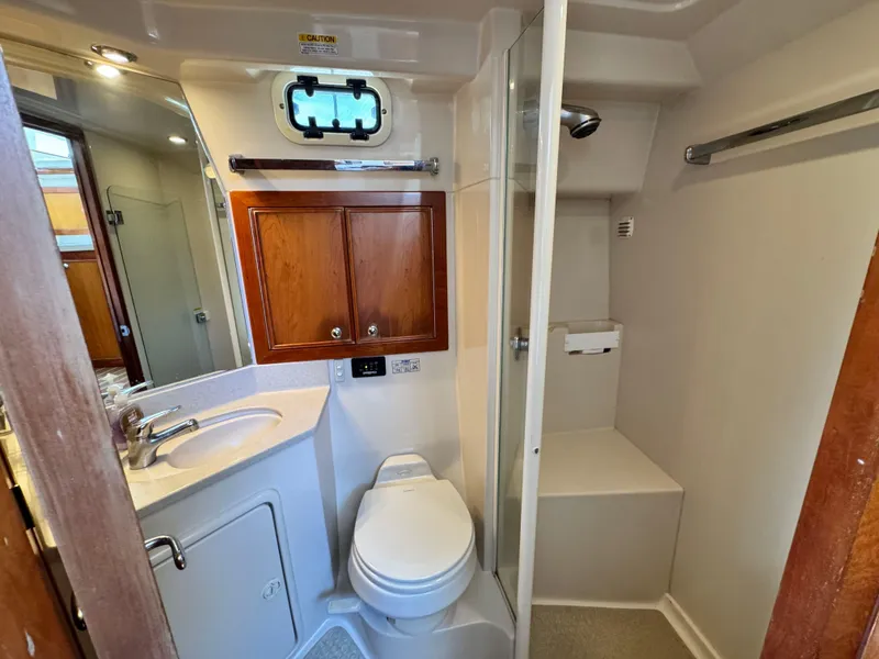 Slide: The Image of 2005 Riviera 33 Flybridge bathroom with sink, toilet, shower, and wooden cabinets. - 34