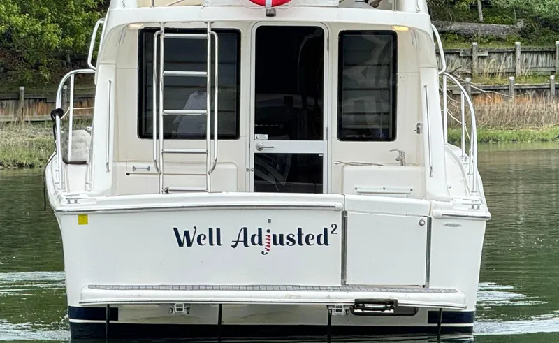 Slide: The Image of 2005 Riviera 33 Flybridge boat named "Well Adjusted" on water, rear view. - 4