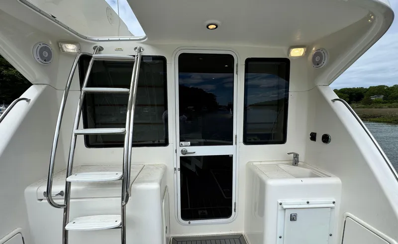 Slide: The Image of 2005 Riviera 33 Flybridge yacht with ladder, door, and outdoor sink area. - 6