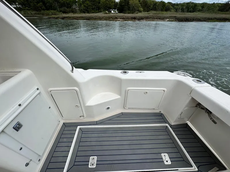 Slide: The Image of 2005 Riviera 33 Flybridge boat deck with storage compartments, near calm water and shoreline. - 9