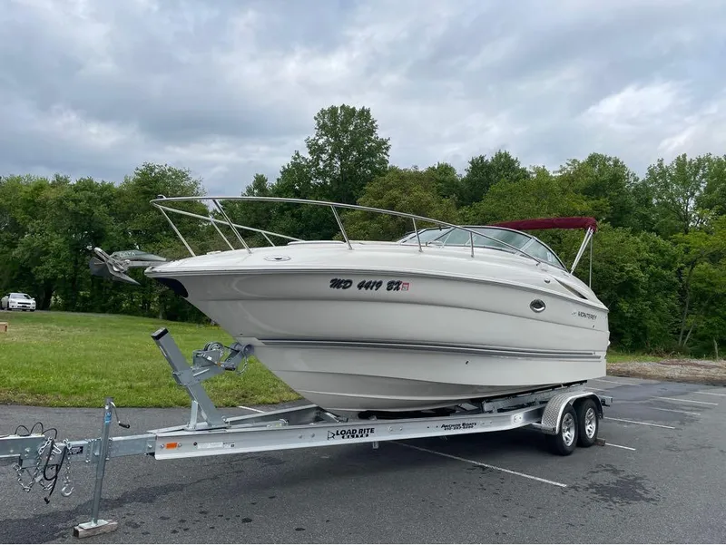 Slide: The Image of 2006 Monterey 250 CR boat on trailer, parked outdoors with trees in background. - 11