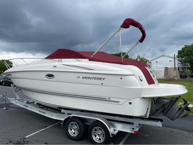Slide: The Image of 2006 Monterey 250 CR boat with maroon canopy on trailer under cloudy sky. - 12