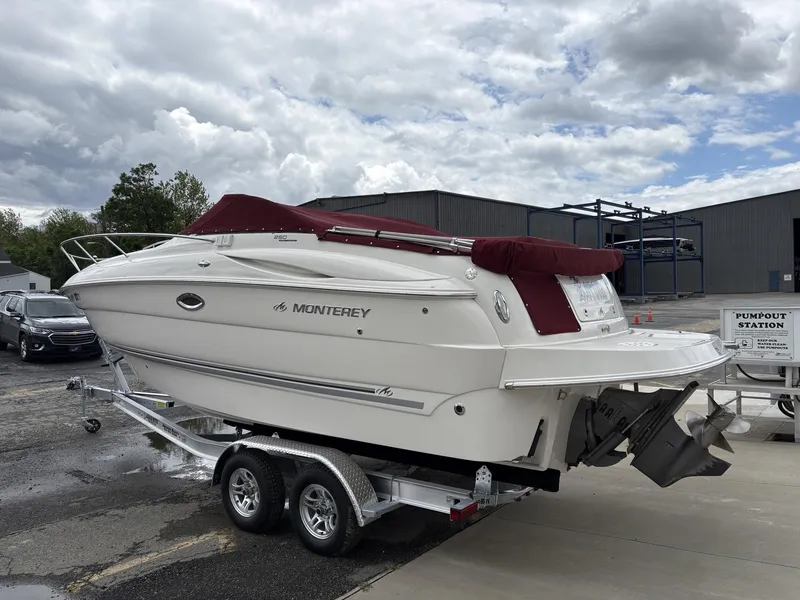 Slide: The Image of 2006 Monterey 250 CR boat on trailer, parked near industrial buildings under cloudy sky. - 23
