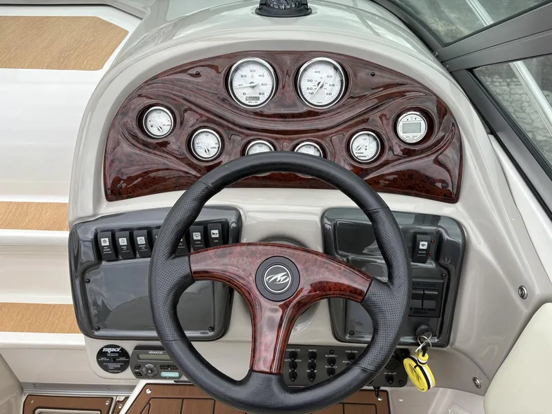 Slide: The Image of Steering wheel and dashboard of a 2006 Monterey 250 CR boat with wood accents. - 25