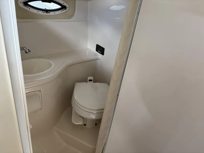Slide: The Image of 2006 Monterey 250 CR boat bathroom with sink, toilet, and porthole window. - 43