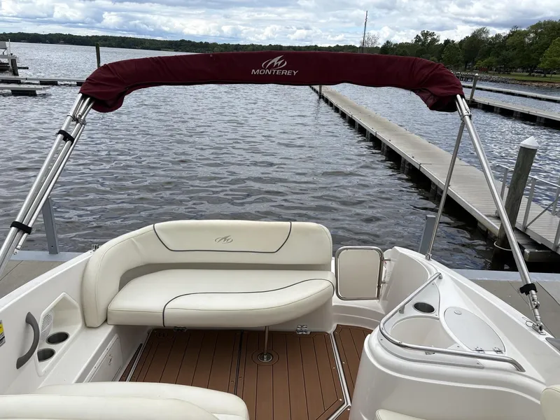 Slide: The Image of 2006 Monterey 250 CR boat with white seating and maroon canopy at a dock. - 44