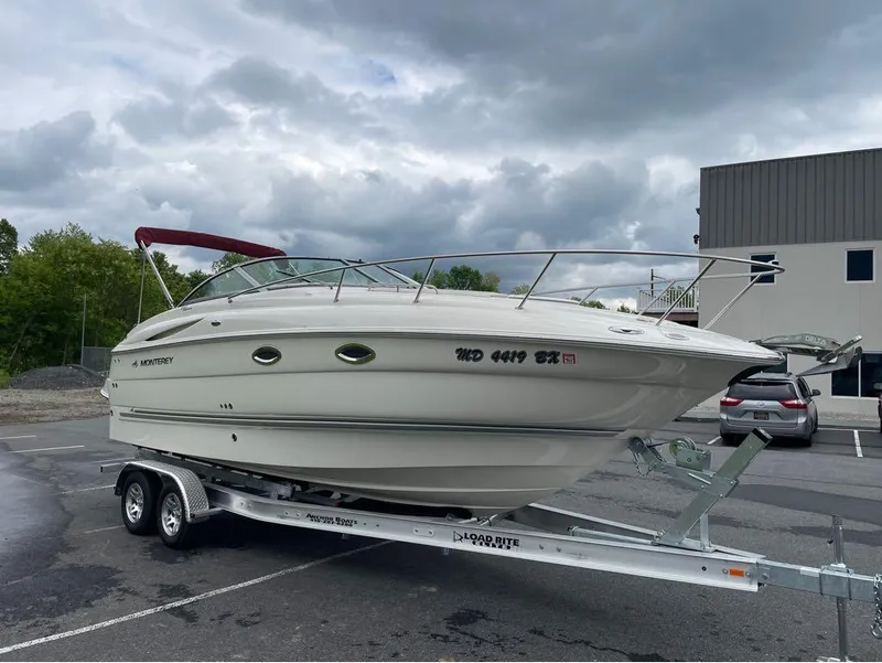 Slide: The Image of 2006 Monterey 250 CR boat on trailer in parking lot under cloudy sky. - 6