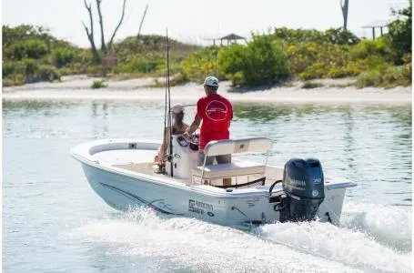 Slide: The Image of 2019 Carolina Skiff 18 JVX CC boat cruising on calm waters near a sandy shoreline. - 13