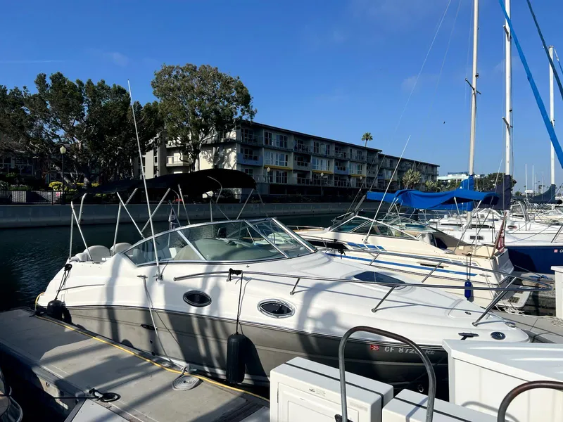 Slide: The Image of 2005 Sea Ray Sundancer docked at marina, surrounded by other boats and waterfront buildings. - 2