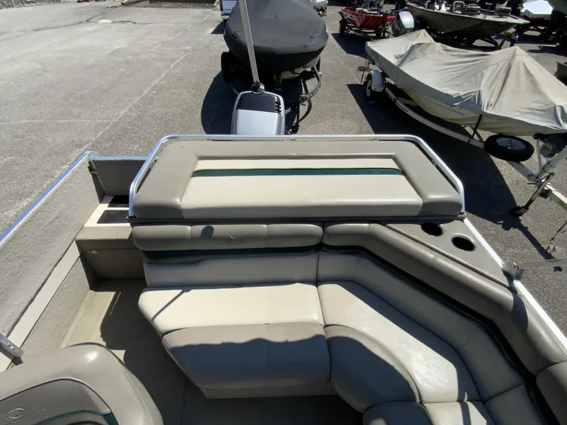 Slide: The Image of 1998 Sun Tracker Party Deck 21 boat with cushioned seating and cup holders, parked outdoors. - 10