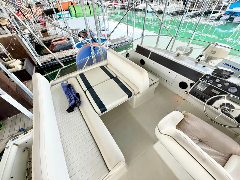 Slide: The Image of 1992 Carver Command Bridge 2828 interior with white seating and control panel, docked at marina. - 19