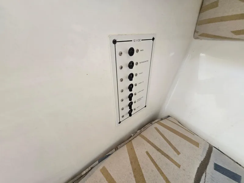 Slide: The Image of Control panel inside 1999 Mako 253 Walk Around boat, featuring multiple switches. - 15