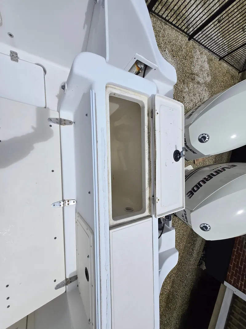 Slide: The Image of 1999 Mako 253 Walk Around boat with open storage compartment and dual outboard motors. - 17