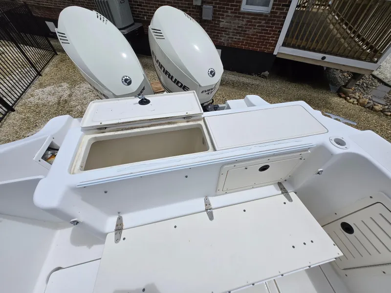 Slide: The Image of 1999 Mako 253 Walk Around boat with open storage compartments and dual outboard motors. - 18