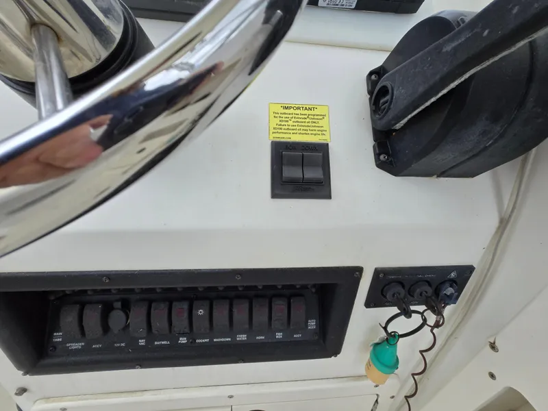 Slide: The Image of Control panel of a 1999 Mako 253 Walk Around boat with switches and steering wheel. - 21