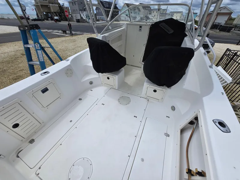 Slide: The Image of 1999 Mako 253 Walk Around boat interior with seating and storage compartments. - 24