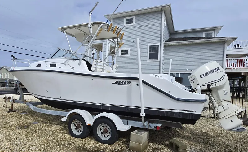 Slide: The Image of 1999 Mako 253 Walk Around boat on trailer, parked near a house. - 4