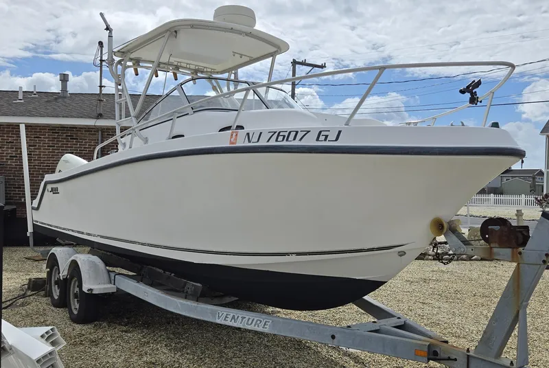 Slide: The Image of 1999 Mako 253 Walk Around boat on trailer, parked outdoors under cloudy sky. - 6