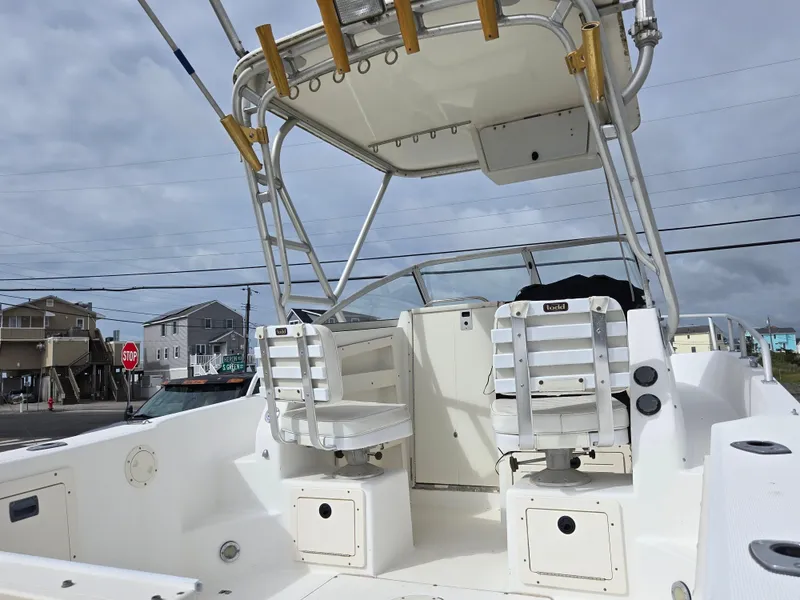 Slide: The Image of 1999 Mako 253 Walk Around boat interior with seating and storage, under cloudy sky. - 7