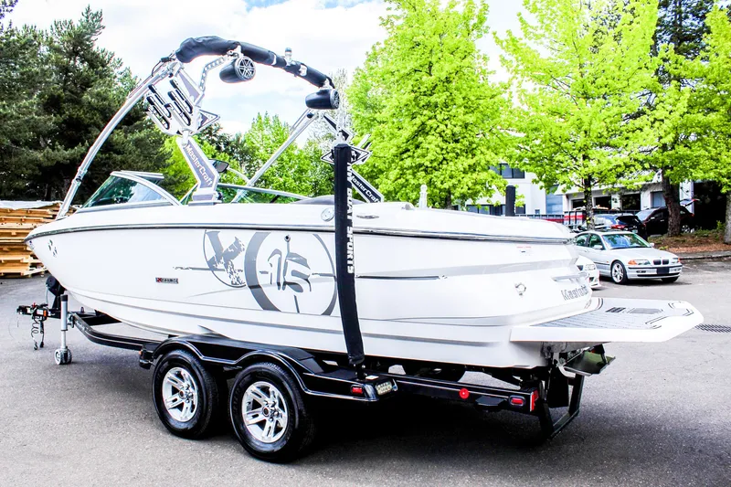 Slide: The Image of 2010 MasterCraft X-15 boat on trailer, parked outdoors with trees in background. - 2