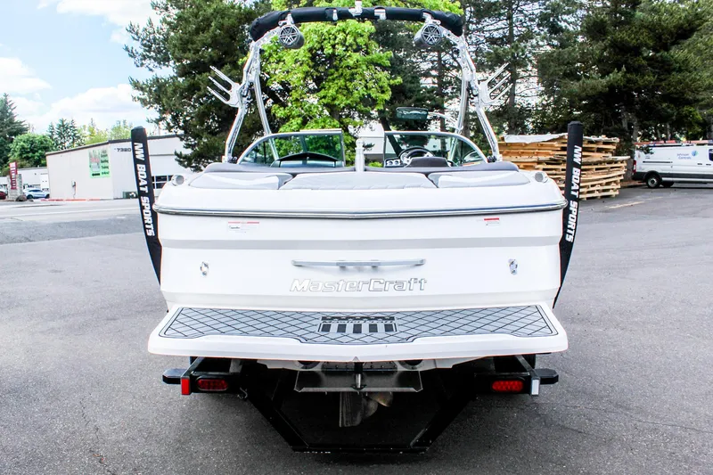 Slide: The Image of 2010 MasterCraft X-15 boat, rear view, parked outdoors with trees in background. - 3