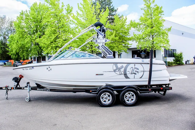 Slide: The Image of 2010 MasterCraft X-15 boat on trailer, parked outdoors with trees in background. - 41