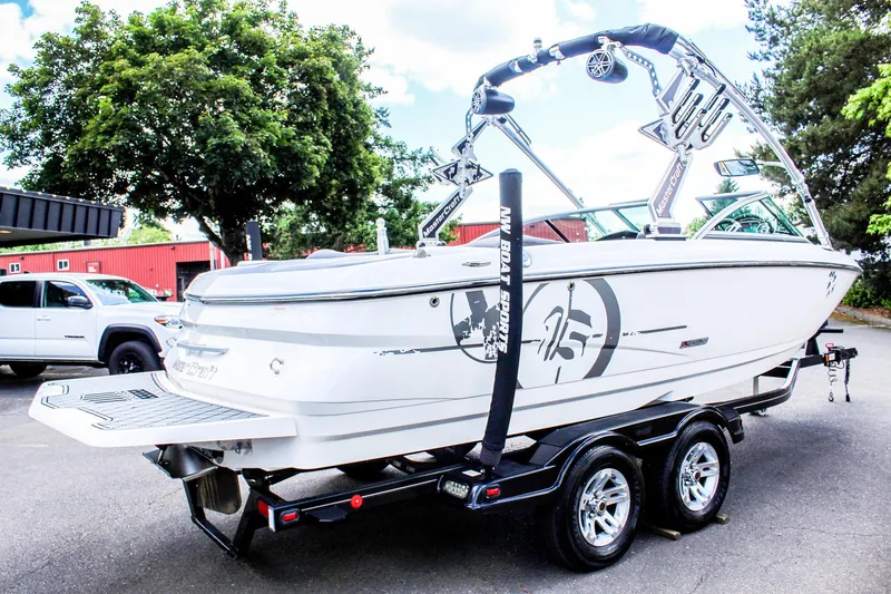 Slide: The Image of 2010 MasterCraft X-15 boat on trailer, parked outdoors, with trees and vehicles in the background. - 5