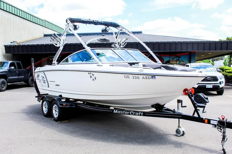 Slide: The Image of 2010 MasterCraft X-15 boat on trailer, parked outdoors, with a building in the background. - 6