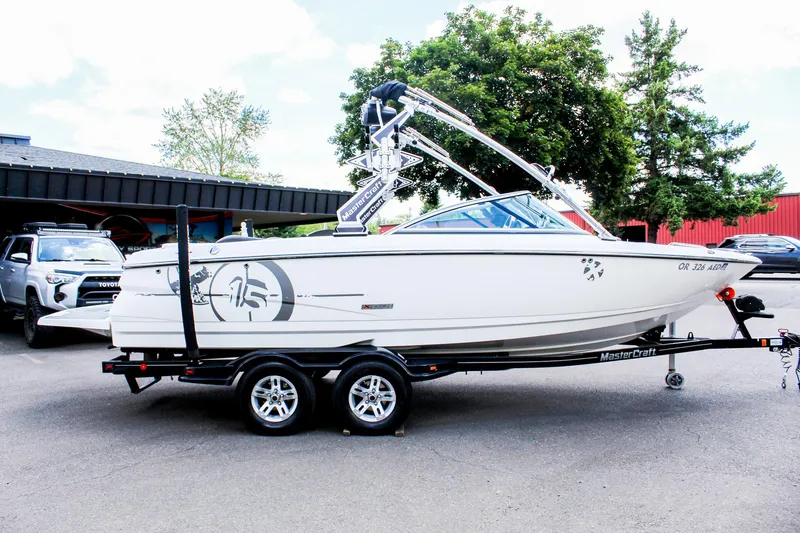 Slide: The Image of 2010 MasterCraft X-15 boat on trailer, parked outdoors near trees and vehicles. - 7