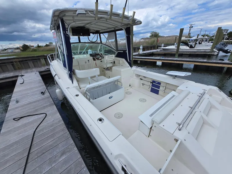 Slide: The Image of 2001 Pursuit 2860 Denali boat docked, featuring spacious deck and seating under cloudy skies. - 1