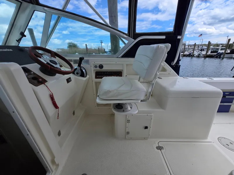 Slide: The Image of 2001 Pursuit 2860 Denali boat cockpit with steering wheel and white seating. - 11