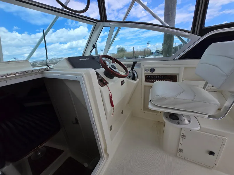 Slide: The Image of 2001 Pursuit 2860 Denali boat interior with steering wheel and white seating. - 12