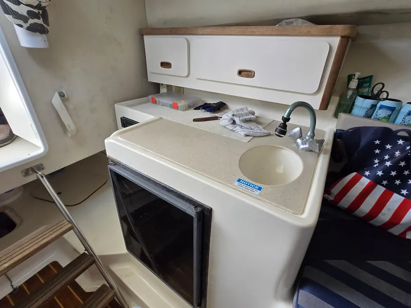Slide: The Image of Compact kitchen area in a 2001 Pursuit 2860 Denali boat with sink and storage cabinets. - 13