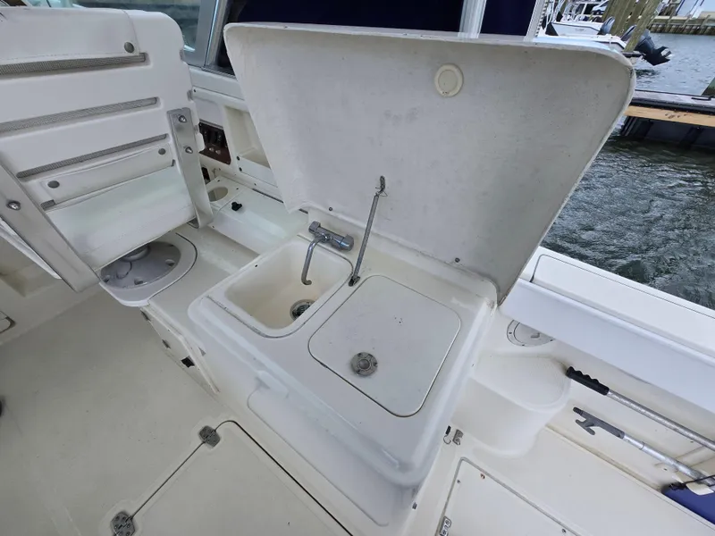 Slide: The Image of 2001 Pursuit 2860 Denali boat sink and seating area, dockside view. - 18